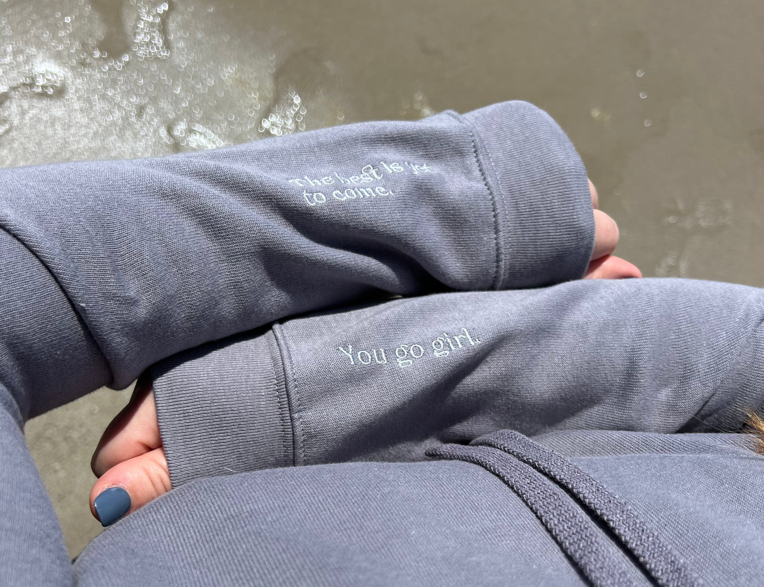Two arms on top of each other showing the embroidery on the sleeves "the best is yet to come" and "you go girl."